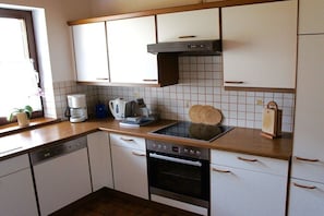 Eine Küche mit weißen Schränken, einem Herd, einer Kaffeemaschine und einem Toaster.