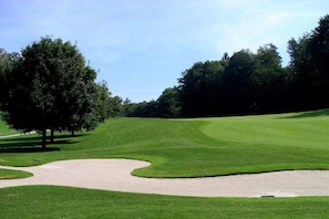 A golf course with a sand bunker, trees, and a clear sky. - Heidi Pfeifhofer - Apt. B (Bodensdorf am Ossiacher See)