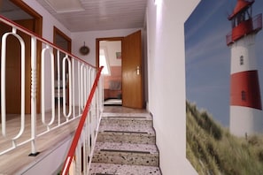 Eine Treppe mit roter Geländer führt zu einem Raum mit einer Tür.