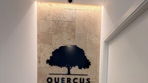A hallway with a wall-mounted sign reading 'QUERCUS APARTAMENTOS' and a tree silhouette.