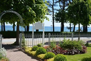 Ein Garten mit weißem Zaun, einem Metallbogen und einer Bank.