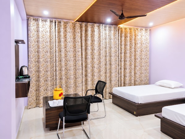 A bedroom with a bed, a desk with a chair, a coffee maker, and a ceiling fan.