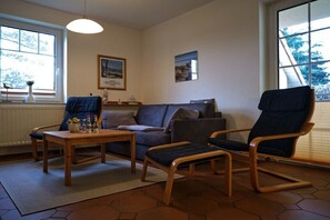 Ein Wohnzimmer mit einer Couch, zwei Sesseln, einem Couchtisch und einem Fenster mit Blick.