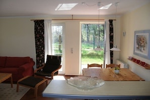 Ein Wohnzimmer mit einem roten Sofa, einem Holzesstisch und einem Glasgefäß in der Mitte sowie einem Sessel.