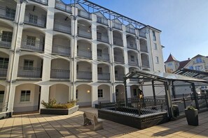 Ein mehrstöckiges Gebäude mit Balkonen, einer überdachten Sitzgelegenheit und einem Innenhof mit Brunnen.