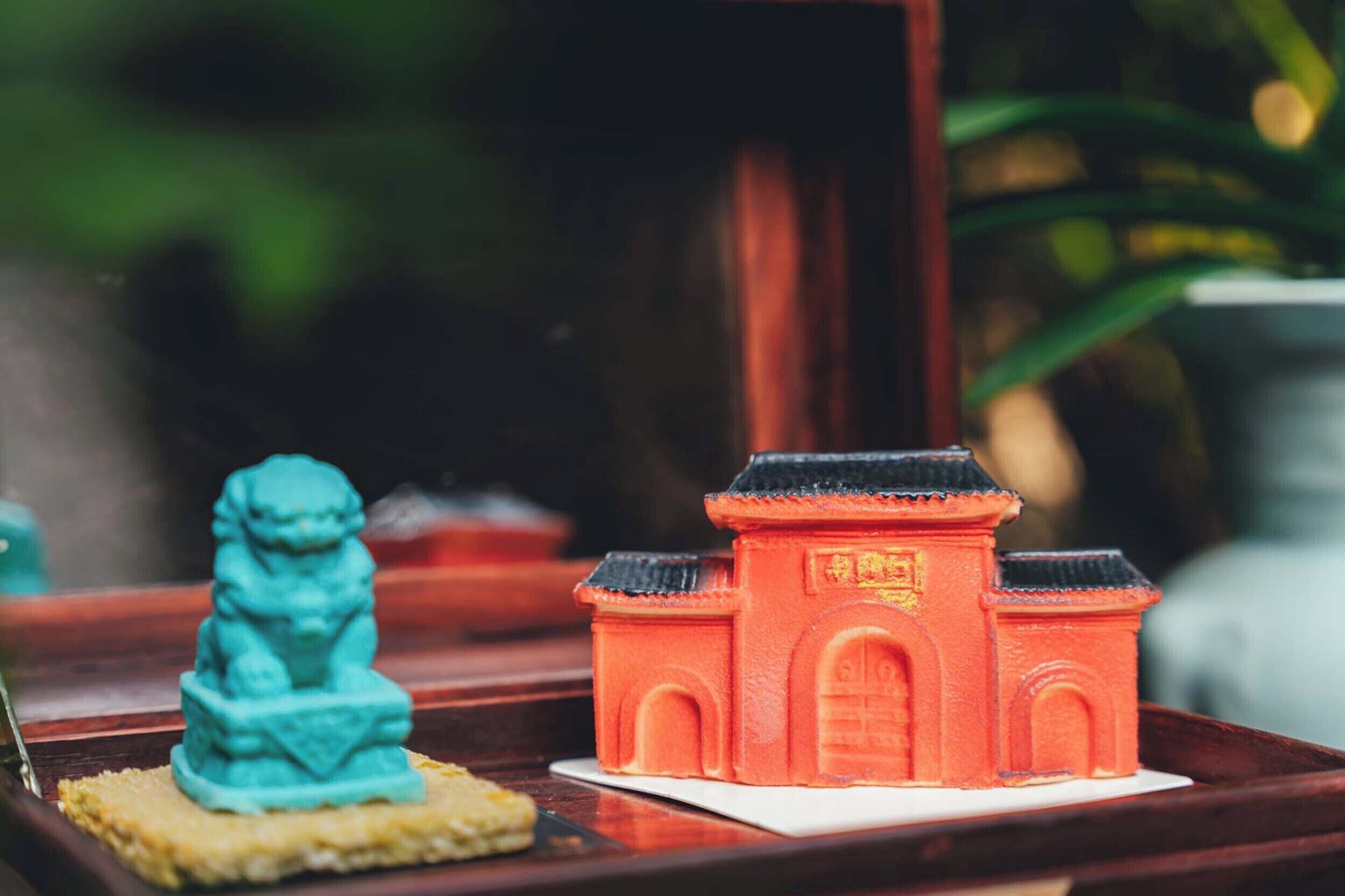 Una maqueta de una construcción tradicional china y una estatua de león sobre una bandeja.