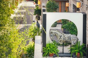 A courtyard with a horse sculpture, potted plants, and a brick building in the background. - Luoyang Yunhuali Hotel (Luoyang)