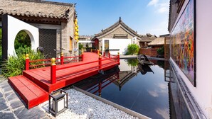 Um pátio tradicional com uma ponte vermelha, um lago e arquitetura clássica.