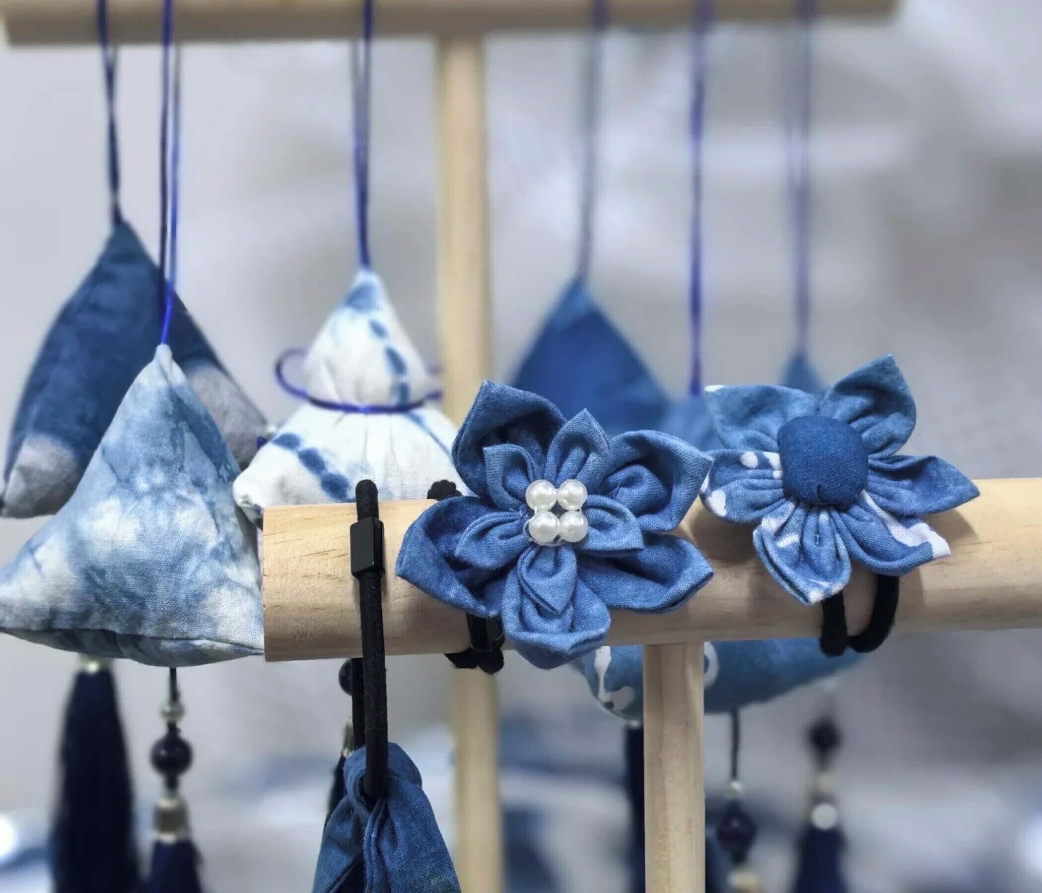 Een presentatie van verschillende blauwe textielartikelen, waaronder kegels en bloemvormige decoraties, hangend aan een houten standaard.