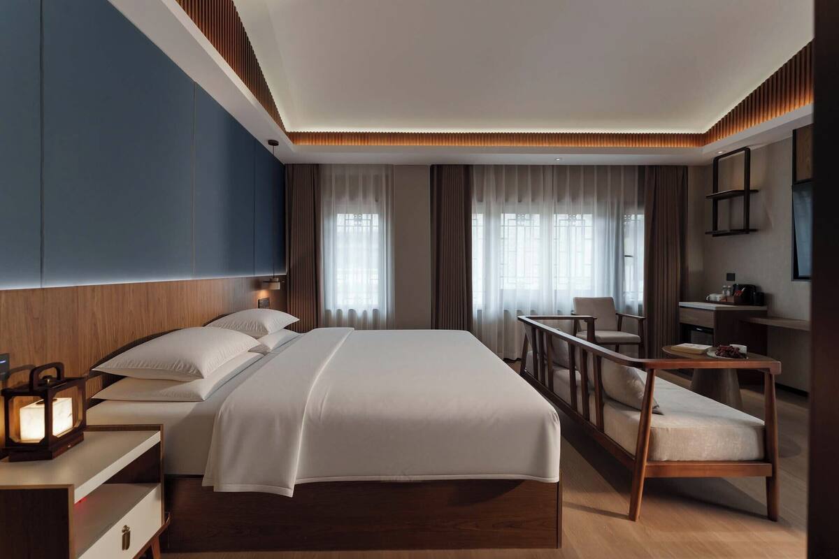 Una habitación de hotel moderna con una cama grande, mesitas de noche, un escritorio y una silla.