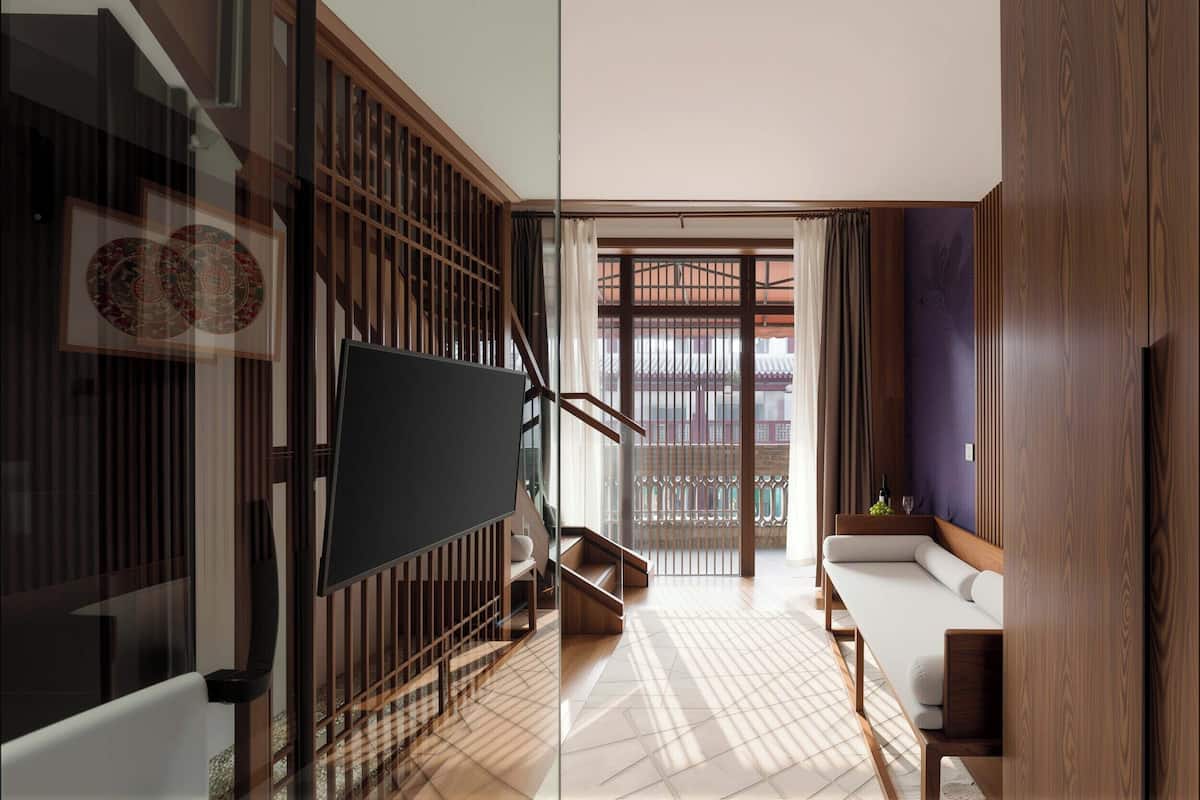 Un interior moderno con sofá, televisor, escalera y vista a través de una puerta de cristal.
