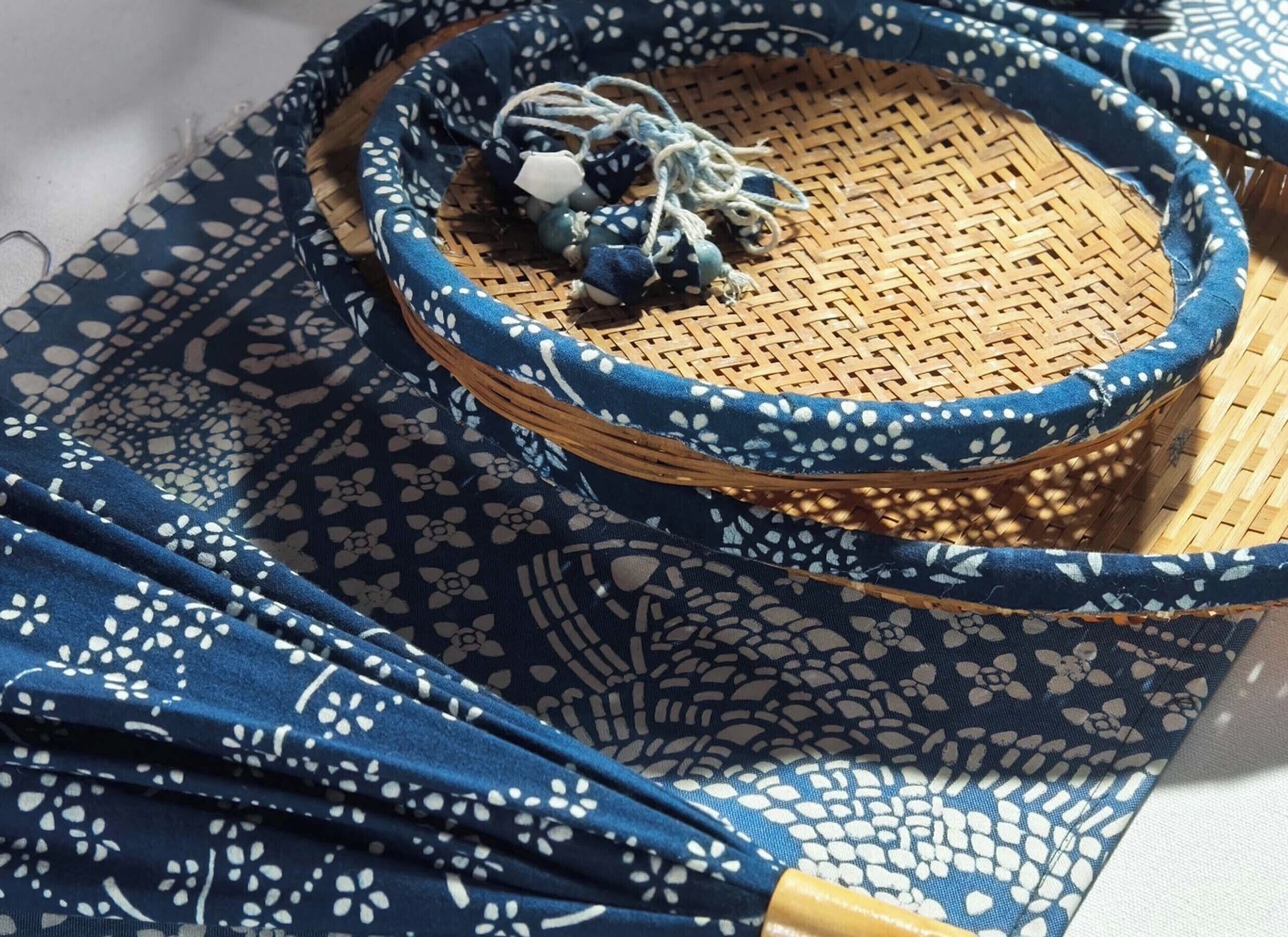 A woven basket with a blue and white pattern, placed on a blue fabric with a similar pattern.