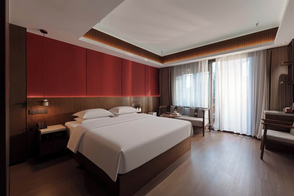 Una habitación de hotel moderna con una cama grande, un escritorio y una zona de estar.