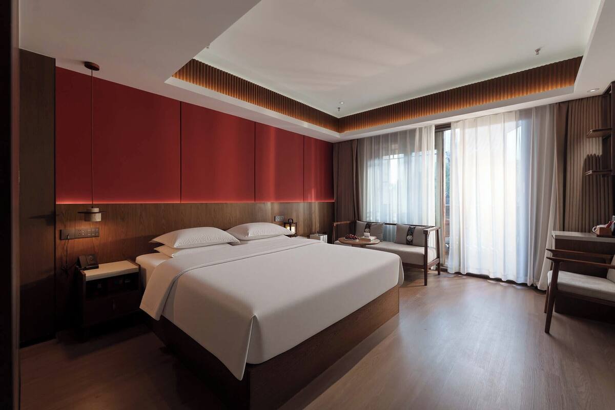 Ein modernes Hotelzimmer mit einem großen Bett, einem Schreibtisch und einer Sitzecke.