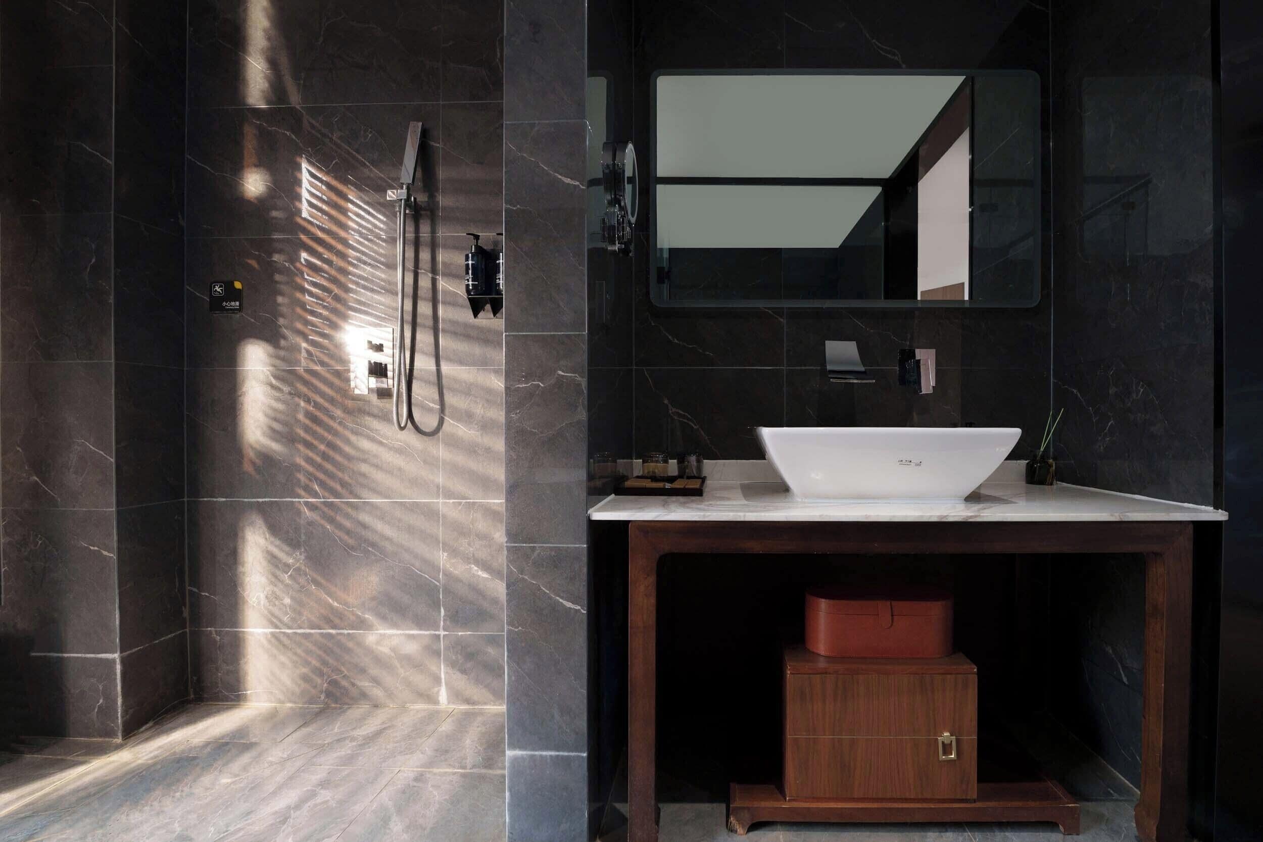 Une salle de bain moderne avec un grand miroir, un lavabo blanc et un espace douche.
