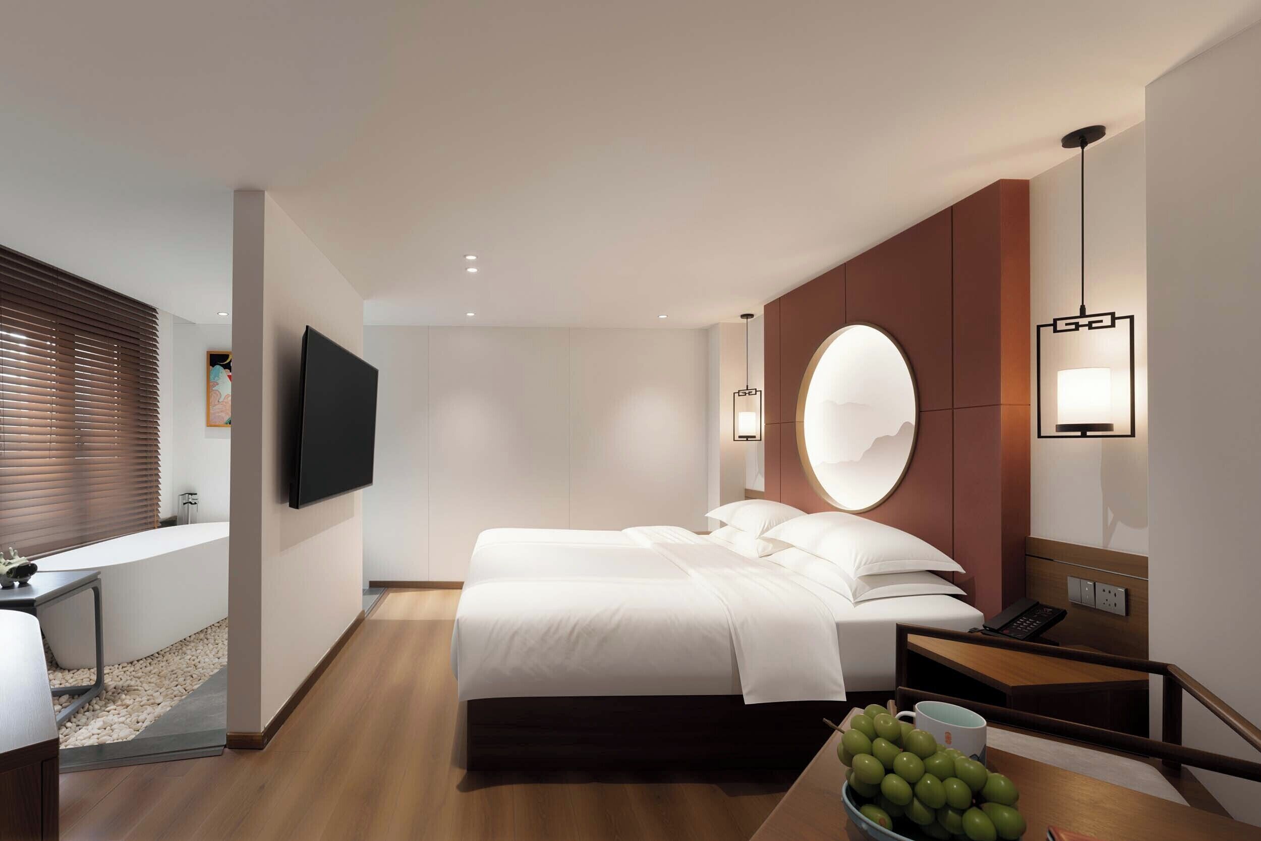 A modern hotel room with a bed, bedside table, lamp, and a TV mounted on the wall.