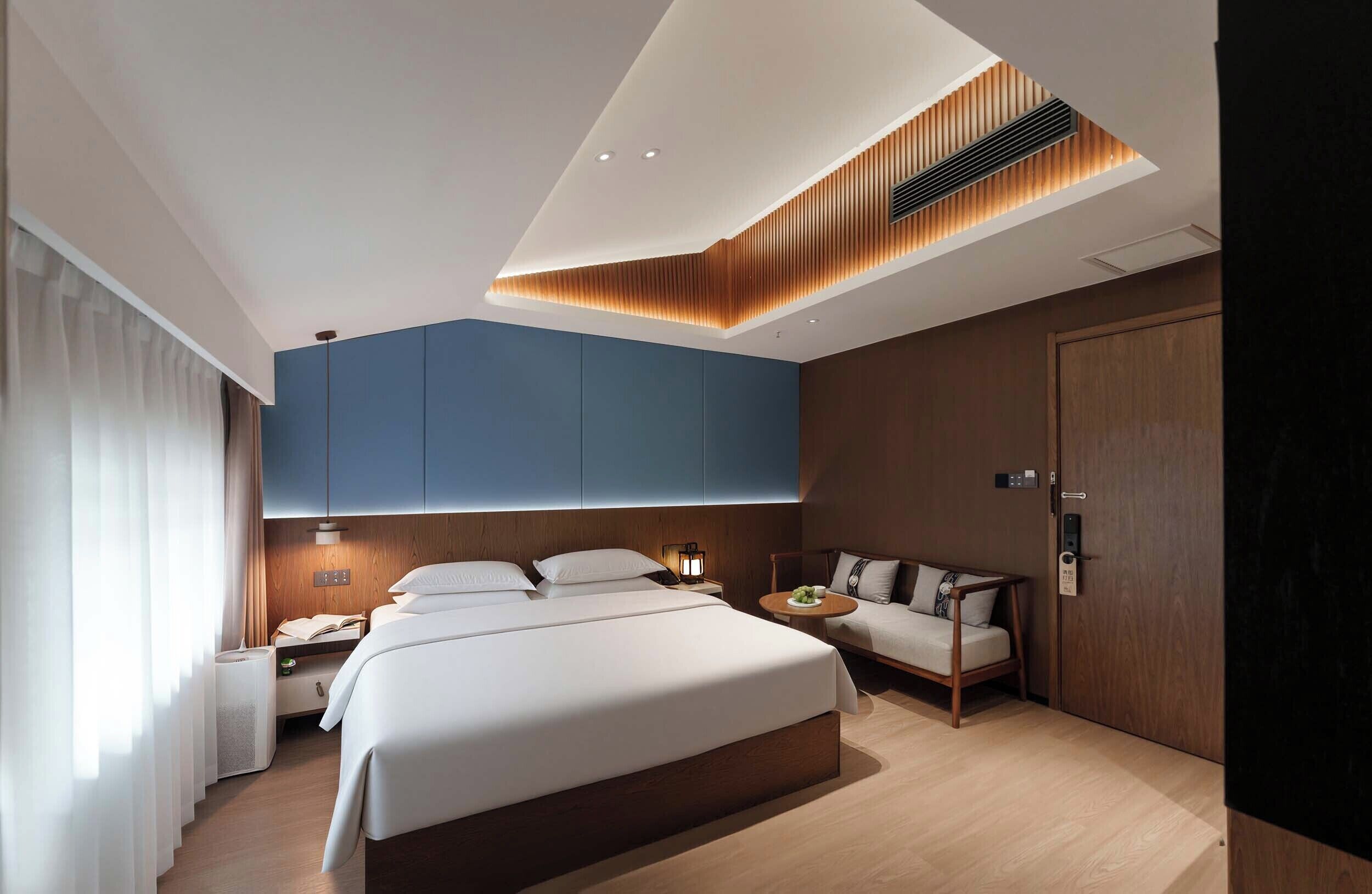Ein modernes Hotelzimmer mit einem großen Bett, einer Couch, einem Schreibtisch und einem Kleiderschrank.