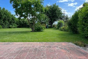 Un patio empedrado con césped y árboles.