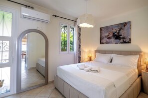Ein Schlafzimmer mit einem großen Bett, einem Deckenventilator, einem Gemälde und Blick durch ein Fenster.