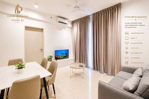 A modern living room with a sofa, a coffee table, a TV, and a dining area. - Iconic Elevated Suite at Trion (Kuala Lumpur)