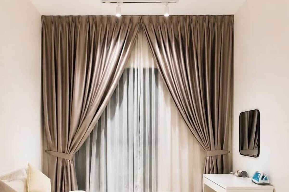 A bedroom with a bed, a desk, and curtains.