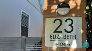 Ein Hausnummernschild mit der Aufschrift '23 ELIZABETH ENTRY', das den Eingang zu einem Anwesen kennzeichnet.