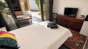 Ein Schlafzimmer mit Bett, Fernseher, Holzschrank und Blick ins Freie.