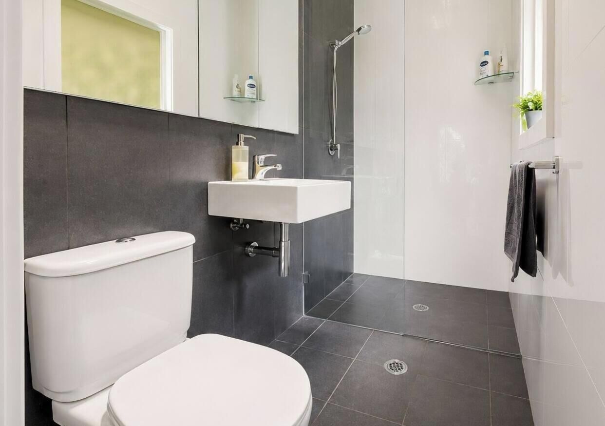 A modern bathroom with a toilet, sink, and shower.
