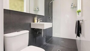 Ein modernes Badezimmer mit Toilette, Waschbecken und Dusche.