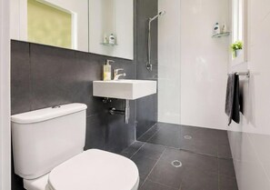 Ein modernes Badezimmer mit Toilette, Waschbecken und Dusche.