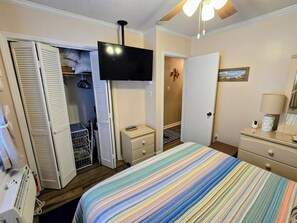 A hotel room with a bed, a TV, a wardrobe, a dresser, and a ceiling fan. - Ocean Front Condo 376 directly on the beach (North Topsail Beach)