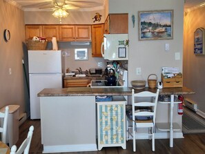 A kitchen with wooden cabinets, a refrigerator, a sink, and a dining area with chairs. - Ocean Front Condo 376 directly on the beach (North Topsail Beach)