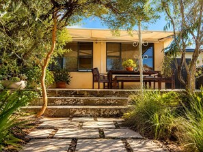 A house with a patio, a table with chairs, and potted plants. - Artistic Parkside Retreat with Deck (South Fremantle)