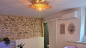 Un dormitorio con una cama grande, una bañera y una pared de piedra.
