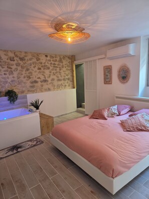 Camera da letto con un ampio letto, una vasca da bagno e un muro in pietra.