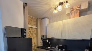 Una cocina moderna con un refrigerador negro, un microondas, una cafetera y un lavaplatos.