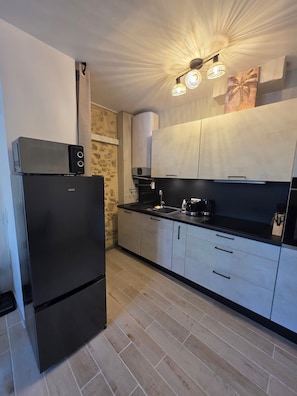 A modern kitchen with a black refrigerator, a microwave, a coffee maker, and a sink. - Le Cocon Provençal balneo Spa. Apartment at the gateway to the Luberon, a Zen interlude (Cavaillon)