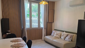 Ein modernes Wohnzimmer mit einer Couch, einem Esstisch, Stühlen und einem Deckenventilator.