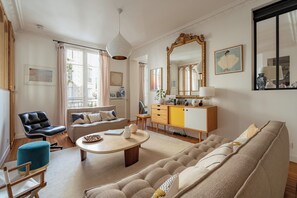 Ein Wohnzimmer mit einer Couch, einem Sessel, einem Tisch, einer Kommode und einem großen Spiegel.