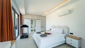 Ein modernes Schlafzimmer mit Bett, Nachttischen, einer Klimaanlage und Blick durch ein Fenster.