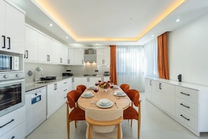 A modern kitchen with white cabinets, a dining table with orange chairs, and a built-in oven. - Just 500 Meters to the Beach: Sea View, Private Pool, 10-Guest Villa in Kışla (Antalya)
