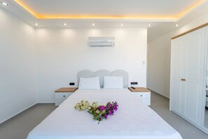 Quarto com cama, mesas de cabeceira, ar condicionado e guarda-roupa.