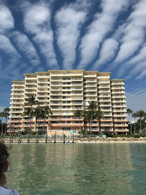 Ein mehrstöckiges Hotel mit Balkonen in Strandnähe, mit Palmen.