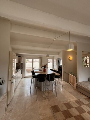 Eine geräumige Küche mit modernen Geräten, ein Essbereich mit Stühlen und ein großes Fenster für natürliches Licht.