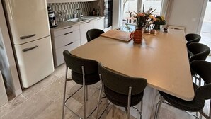Eine moderne Küche mit weißen Schränken, einer großen Kochinsel mit Stühlen und einer Pendelleuchte.