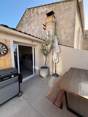 A patio with a grill, a wooden table, a potted tree, and a dartboard. - Endoume - Town house 140 m² - Large terrace & private garage (Marseille)