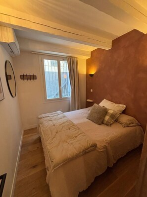 A bedroom with a bed, a window with curtains, an air conditioning unit, and a wall-mounted light fixture. - Endoume - Town house 140 m² - Large terrace & private garage (Marseille)