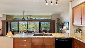 A kitchen with a large window, a dishwasher, and a dining area with outdoor seating. - 2BR, 2BA Kaanapali Royal condo with pool, hot tub, kitchen, AC-Kaanapali Royal F302 (Lahaina)