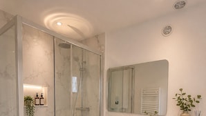 A modern bathroom with a glass-enclosed shower, a white vanity with a mirror, and a toilet. - COSY, FULLY-EQUIPPED APARTMENT (Paris)