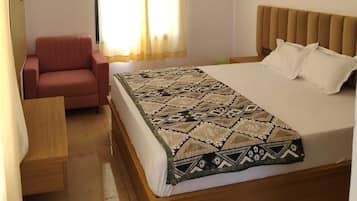 Quarto com cama, cadeira, ventilador de teto e janela com cortinas.